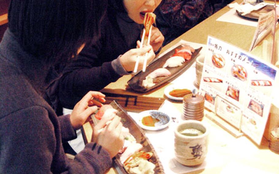 Customers stop by a small sushi restaurant for some fresh food.
