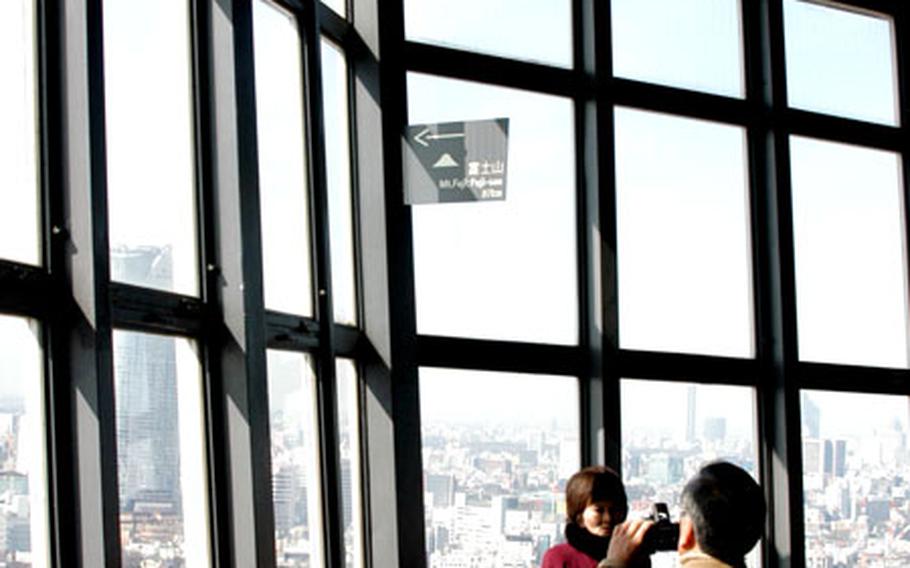 A pair of Tower tourists snap a picture from the Main Observatory, with the new Roppongi Hills building in the background.