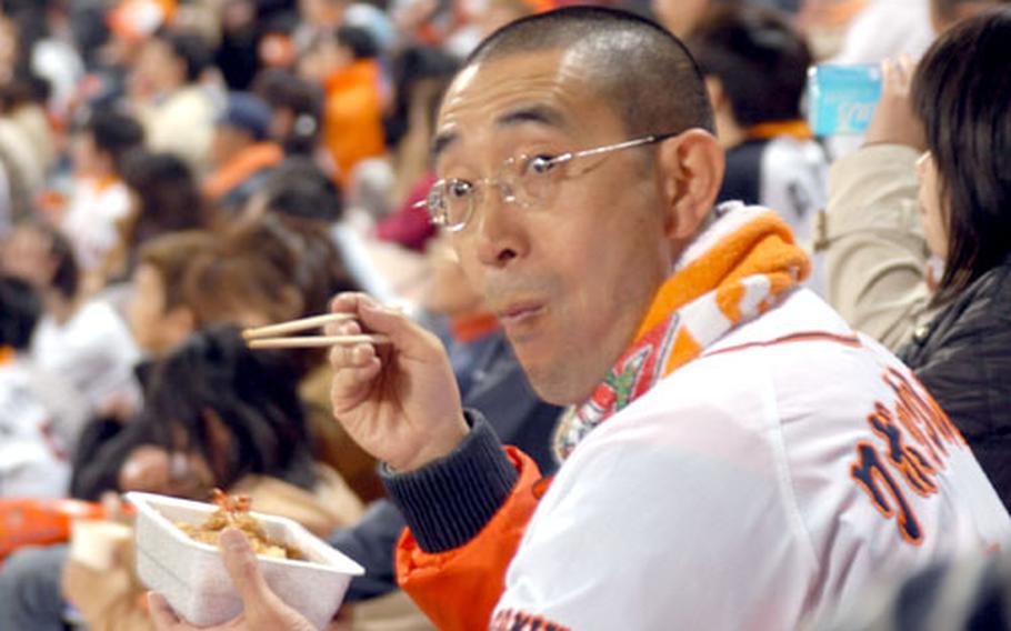 A Giants fan enjoys a snack of tempura during the game. Stadium food in Japan is a bit different than what fans would expect in the States.