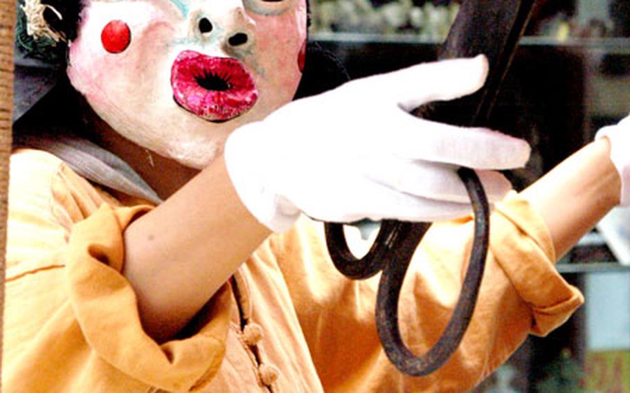 A woman slices candy with big scissors. She uses the costume, dance and tape-recorded music to attract customers and says it makes the treats come out well.