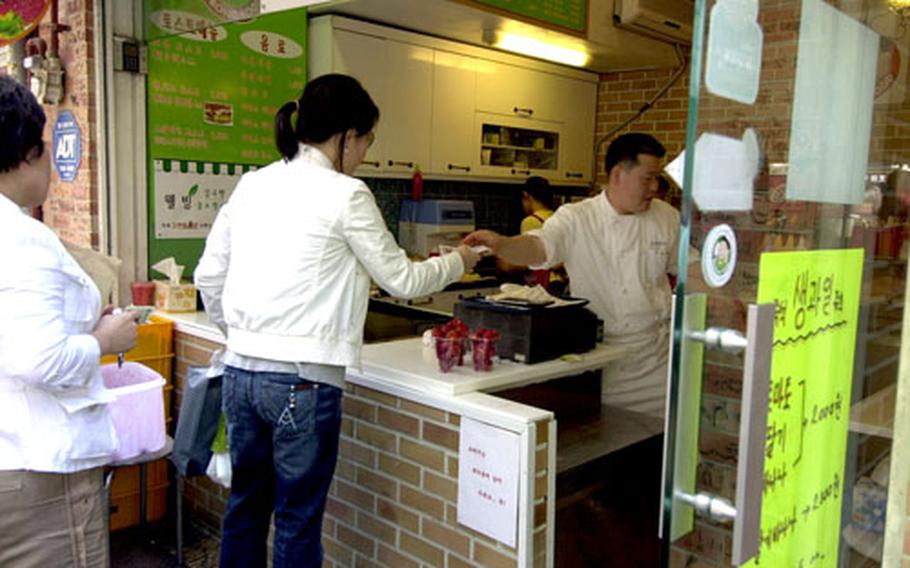 A customer purchases cups of fruit from a vendor.