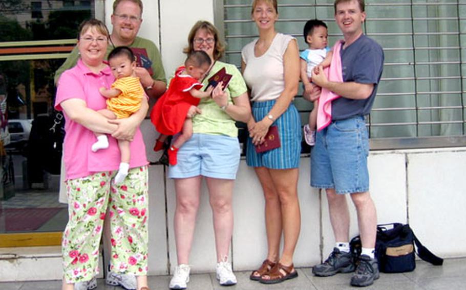 Adoptive parents and their new daughters pose in front of Nanchang’s police station, where the babies were issued their new Chinese passports.