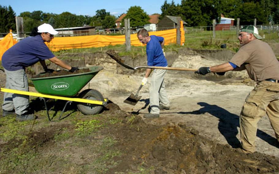 Members of the Joint POW/MIA Accounting Command recovery team members — from left, Air Force Tech Sgt. Linda Williams, and anthropologists Andy Tyrrell and Derek Benedix — shovel dirt at the crash site.