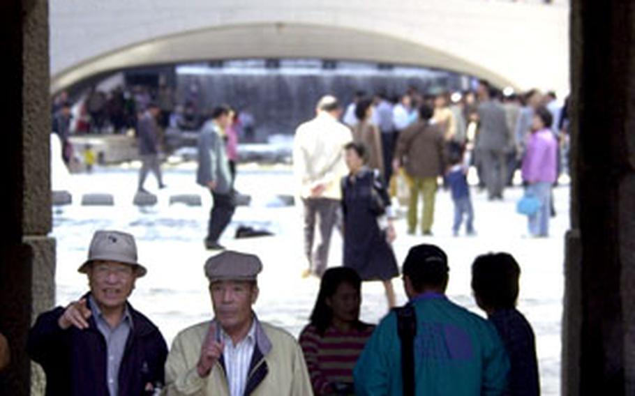 South Koreans walk under a bridge along the Cheonggye Stream in downtown Seoul.