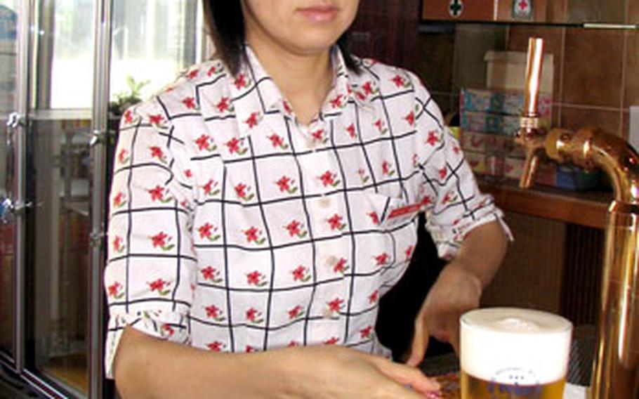 Nachiko Higa serves up an ice-cold glass of beer after a mouth-watering tour of the Orion Brewery in Nago, Okinawa.