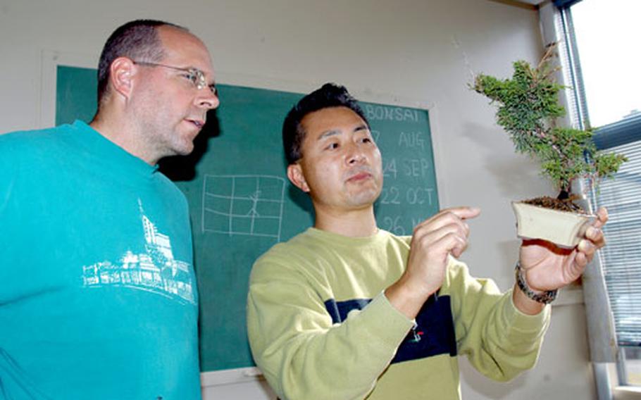 Bonsai instructor Satoru Yamauchi, right, holds up student Brett James’ bonsai plant during a recent class at Misawa Air Base, Japan.