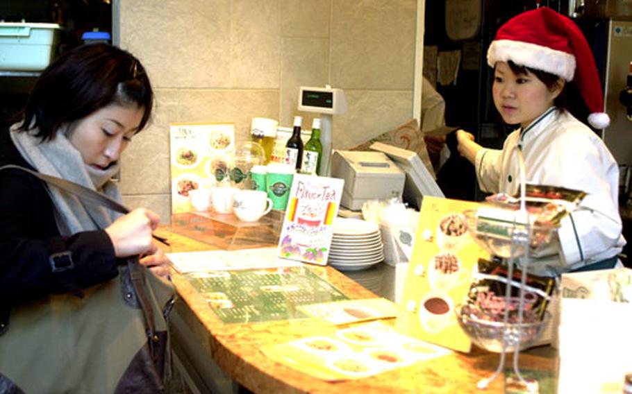 A worker at a coffee shop in Roppongi wears a Santa hat, demonstrating the Christmas influence in Japan.