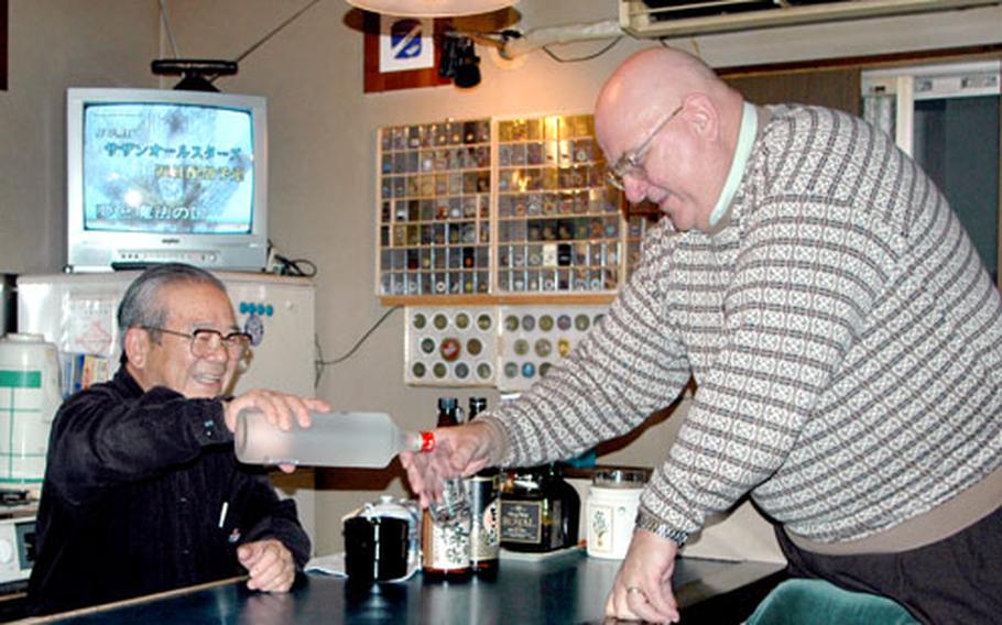 Pub Royal owner Takehisa Seki, left, who also is vice president of Sasebo Naval Base’s Navy League Council, serves a shot of vodka to Jerry Havens from the base Fleet and Family Services Center, who also is president of Navy League.
