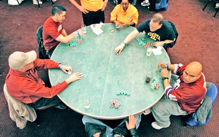 Players gather around a table for one of the games. The 374th Services Division director, Robyn Sleeth, says Texas Hold ’Em tournaments will become a quarterly staple at Yokota. He envisions some day bringing together base champions from across the Pacific for a one-table showdown.