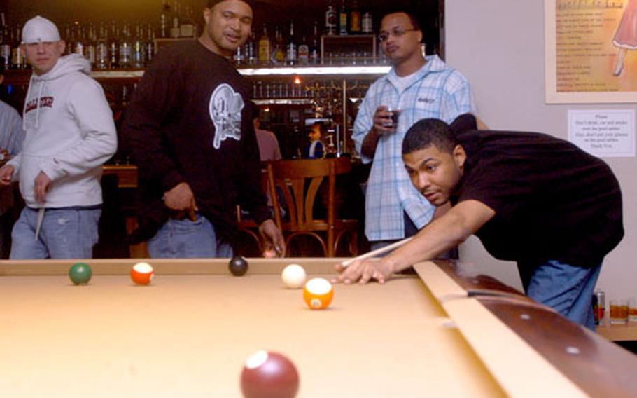 Air Force Staff Sgt. Tito Rosario lines up a pool shot while a few of his buddies watch at Conway’s in Jurbise, Belgium.