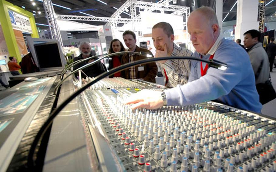 Trade show visitors check out an Altair Audio soundboard used for mixing audio.