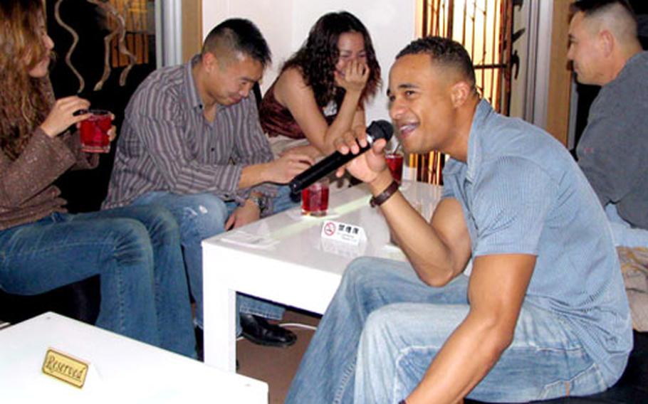 Marine 2nd Lt. Michael McFarland hits an off-key note during a karaoke solo at Chatan’s NiCHe Cafe and Bar. His friends laugh appreciatively.
