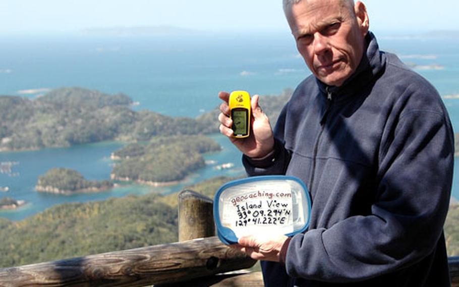 Walter Birkenheier, director of Sasebo's Outdoor Recreation Center, displays a Global Positioning Device and a Geocache container at one of Sasebo's geocache sites, about 1,000 feet above sea level atop Mt. Eishidake in Sasebo.