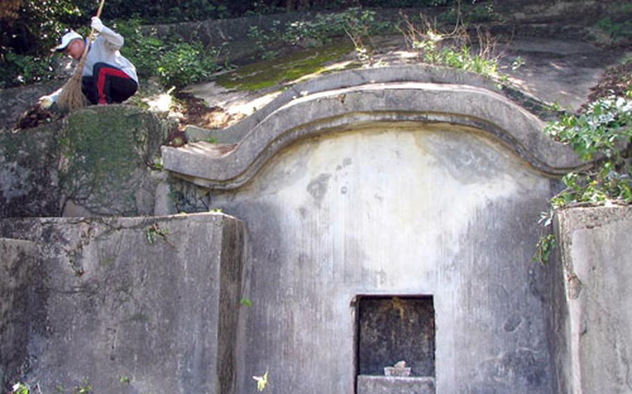Isao Tsuha cleans brush from his family's centuries-old tomb on Okinawa in preparation for the annual shima festival, a time when families gather at the tombs of their ancestors for prayers, good food and a good time.