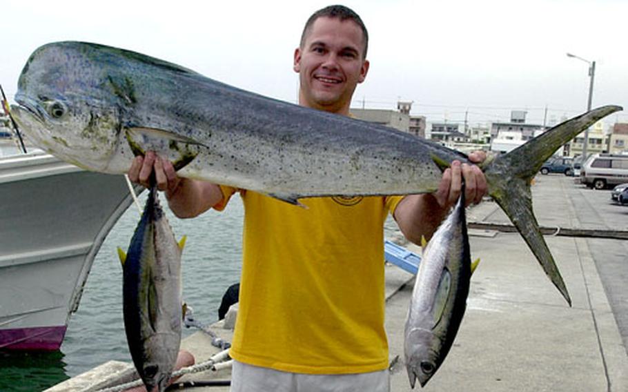 Navy Lt. James Quick holds up his catch, a mahi mahi and two yellow fin tuna, after a recent fishing trip from the Nakagusuku Port.