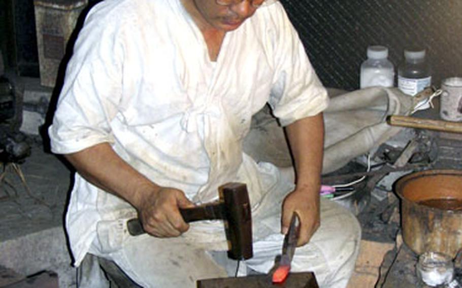 Okinawa sword maker Kiyochika Kanehama pounds on a bar of red-hot raw steel during the early stages of fashioning a Japanese katana sword.