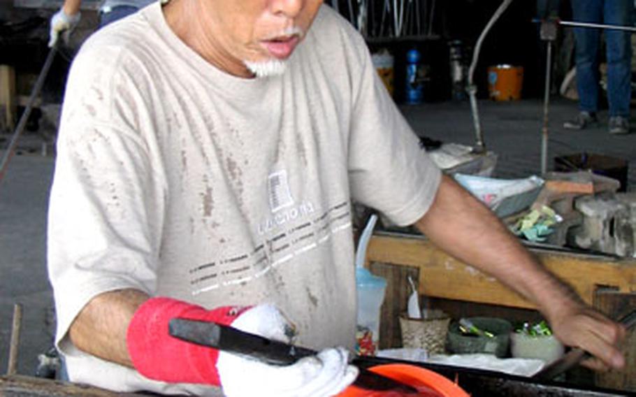 Glassmaking artist Seikichi Inamine, 66, works on a bowl at his Mid-Air Glass Blowing Studio Rainbow in the Yomitan Pottery Village on Okinawa.
