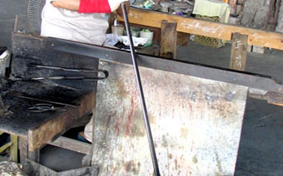 Seikichi Inamine blows molten glass into shape at studio in Yomitan, Okinawa. Inamine is the only Okinawan glassmaker to continue to use recycled bottles as the base material for his works of art.