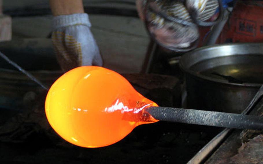 A red-hot ball of glass is shaped in the early stages of making a bowl at the Mid-Air Glass Blowing Studio Rainbow in the Yomitan Pottery Village on Okinawa.