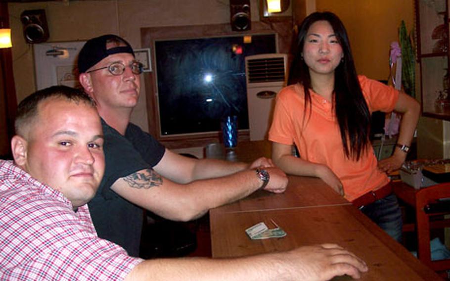 Full House owner Sophia tends the bar while Tech. Sgt. Brian Lubiejewski, back, and Senior Airman Trent Falcione stop in for a “juicy-free” drink at the bar in A-Town, near Kunsan Air Base, South Korea.