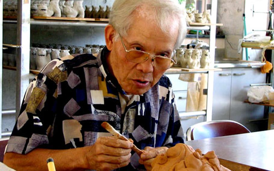 Okinawa pottery artist Jouei Shimabukuro, 63, works on a clay shisa faceplate in his Naha City Traditional Craft Pavilion workshop.