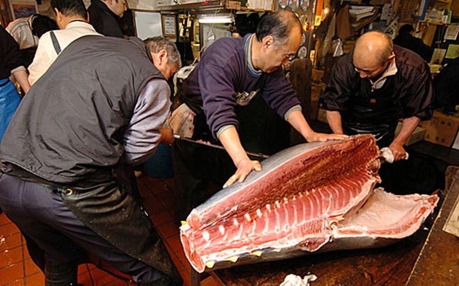Japanese vendors slice up a tuna worth about $10,000. The tuna weights about 85-100 lbs.