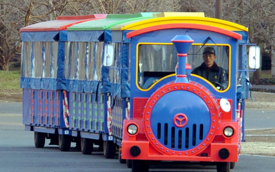 Japanese patrons ride in a trolley that tours around the park during a chilly winter evening.