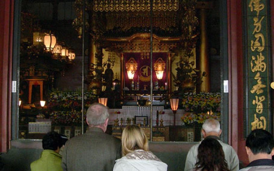 Patrons pray inside of Sensoji Temple. The temple is Tokyo&#39;s oldest and a short train ride from the city&#39;s center.