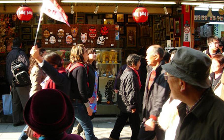 Shops line the street leading up to Sensoji Temple. Here, a tour guide leads a group past a souvenir shop.