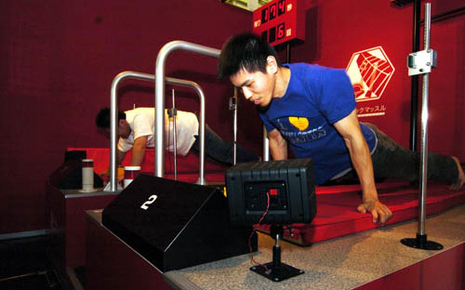 Japanese visitors do pushups in a competition set up at Muscle Park. patrons play games set up to enjoy and get a physical workout. Muscle Park is located in the Odaiba area of Tokyo.
