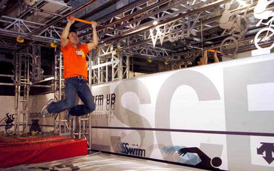 An employee of Muscle Park shows visitors how to use an obstacles course built to challenge upper body strength and coordination.