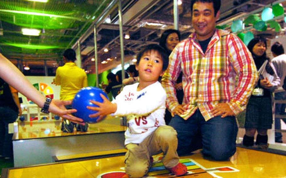 A young father helps his son play a tricky bowling game at Muscle Park.