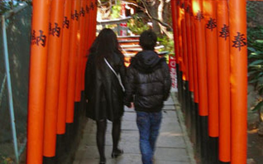 A Japanese couple walks through archways to a shrine in Ueno Park.