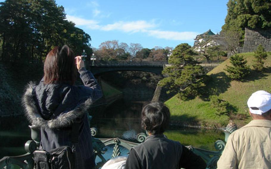 Visitors take photos of the Imperial Palace from outside the gates with their friends and loved ones. From this view, visitors can sometimes see the royal family’s motorcade.