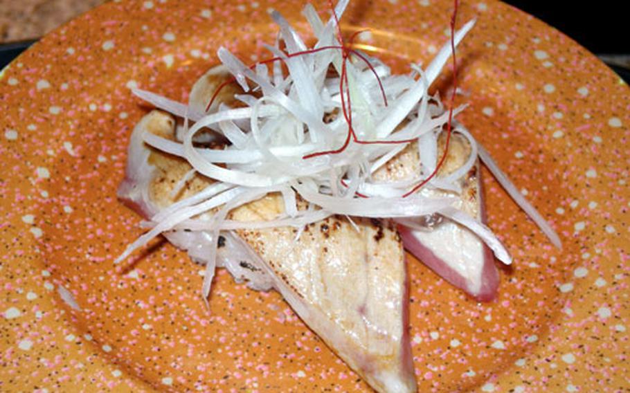 Abute Toro, or cooked tuna sushi, resides on an orange plate.