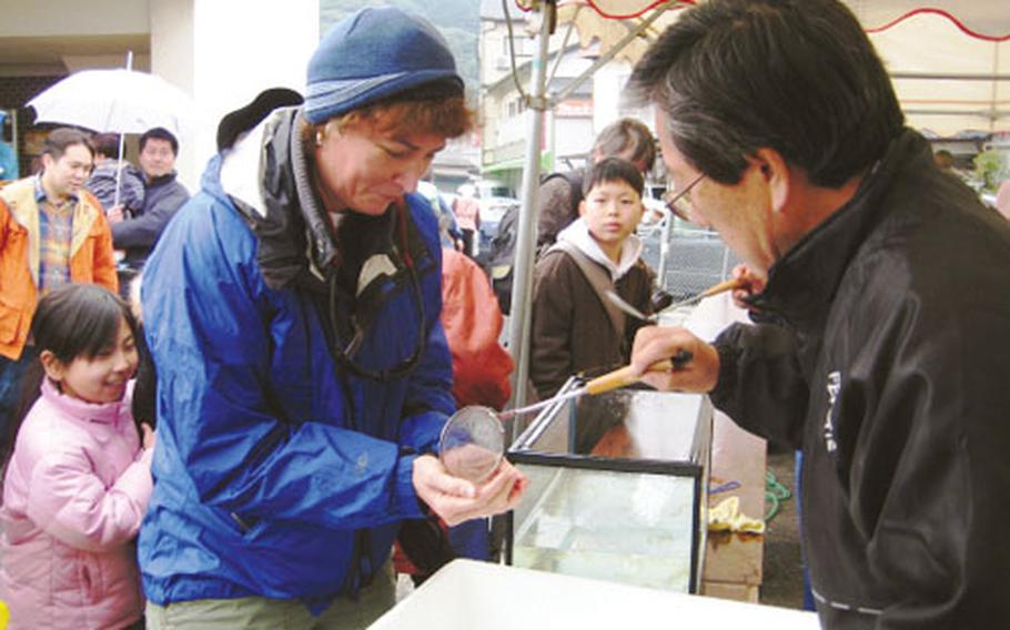 Adventurous traveling companion Kelly Kirby receives a live fish at Kyushu’s “dancing fish festival.”
