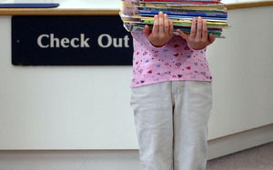 Hannah Bennett, 6, holds books at Ramstein Elementary School. Hannah is wearing a Pony Tails shirt, Lee jeans and Sam & Libby shoes from the Army and Air Force Exchange Service base exchange on Ramstein Air Base.
