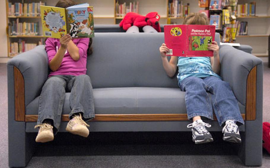 Calin Petro, 7, sporting a Pony Tails shirt, jeans and North Side tennis shoes on the left and Kaelin Gould, 6, wearing a Beautees shirt, jeans and Skechers tennis shoes strike a pose in the Ramstein Elementary School library.