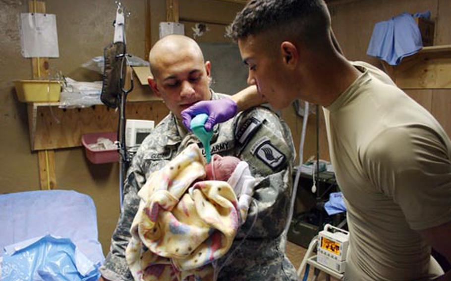 Staff Sgt. Justin Guizar, left, and Spc. Joshua Ashford care for an Afghan infant that they delivered at an aid station. The child's mother was pregnant and injured in a Taliban rocket attack and the soldiers treated her injuries as well as those the baby suffered during the attack.