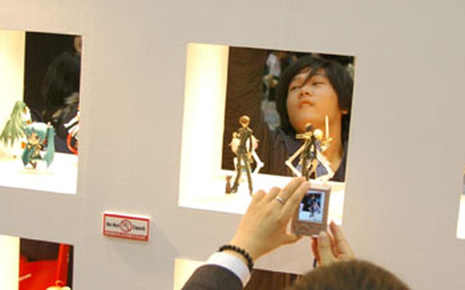 Anime fans take pictures of figurines on display at the 2009 Tokyo International Anime Fair.