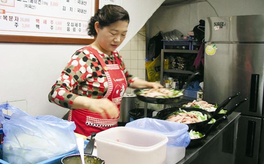 At the Kim Neh Jeep restaurant, owner Kim Myong-ja readies pans of the house specialty, "bu-tehchi-geh," a spicy stew that came about during the hard days of the Korean War.