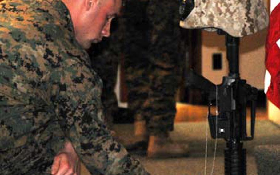 Third Reconnaissance Battalion Marine Sgt. Tyler Van Hook, 20, holds onto the dog tags of Sgt. Michael H. Ferschke Jr., 22, for a moment of remembrance at Ferschke’s memorial Feb. 20 on Camp Schwab, Okinawa.