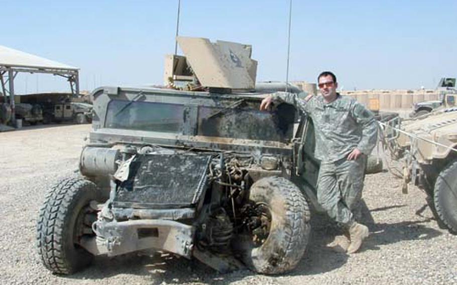 Spc. Jason Harrington of the Pennsylvania National Guard poses with the Humvee that was blown up under him during an incident in Ramadi, Iraq, on Sept. 19, 2005.