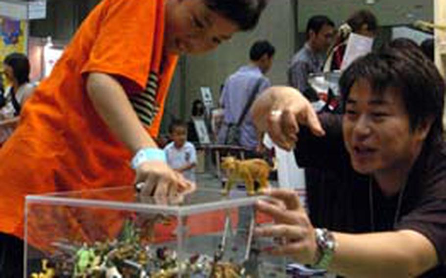A visitor tries to grab as many dinosaur figures as he can out of a box July 18. Exhibitors held games such as this, as well as showcasing the latest toys, during the expo.