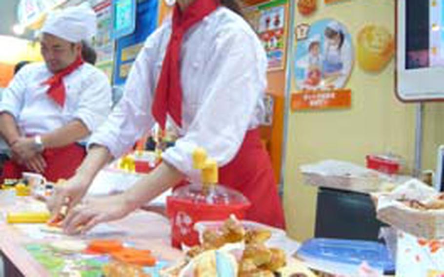 Exhibitor at Bandai booth demonstrates making bread shaped in Anpanman, a popular animation character. The set includes utensils such as mixing bowl, measuring cup and Anpanman pastry cutters. It goes on sale this fall.