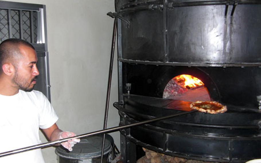 Daisuke Nakamura, chef and owner of Bacar, carefully but quickly takes a pizza out of the oven. He firmly believes that only a wood-fired oven can bake a perfect pizza.