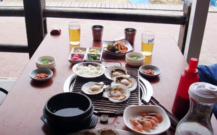 A plate of scallops fresh from the tank waits to be cooked on a table grill at Seoul Hoe Chip — in English, Seoul Raw Fish House — overlooking Pusan’s popular Haeundae beach.