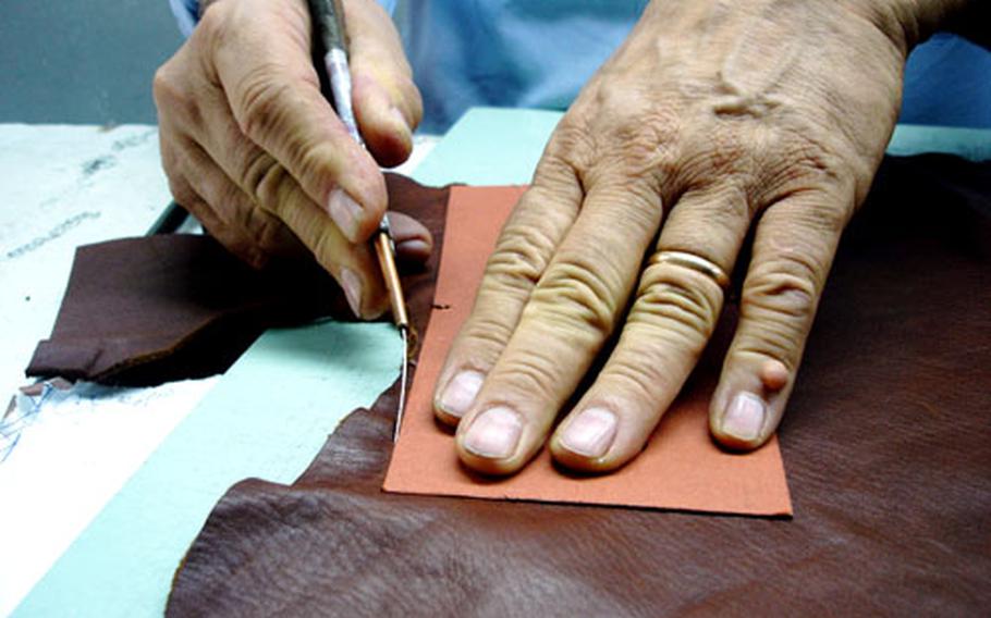 A tailor scores and cuts a leather panel that will become part of a coat made at the GF clothing shop in downtown Naples.