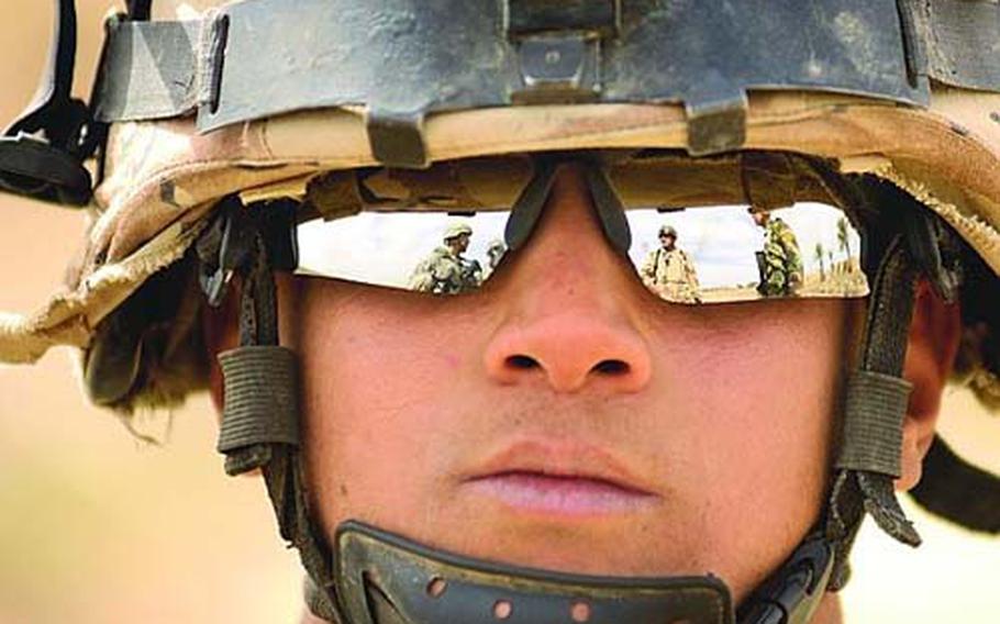 First Lt. Javier Avila, 3rd Platoon leader for Company A, Task Force 3-66 Armor, and Lt. Zafer from the Iraqi army are reflected in the glasses of Iraqi army Pvt. Raad Gabar as they coordinated a patrol in February in the village of Tahweela.