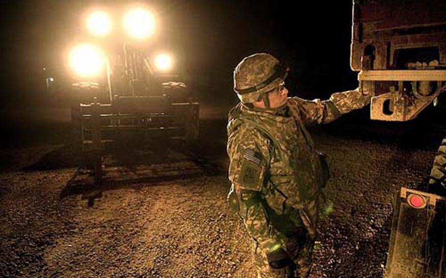 Pfc. Christopher Trumbull, a soldier assigned to the 172nd Support Battalion, secures a cargo container for transport during a late-night convoy in February at Forward Operating Base Iskan. U.S. forces were in the midst of preparing to turn the base over to the Iraqi Ministry of Electricity.